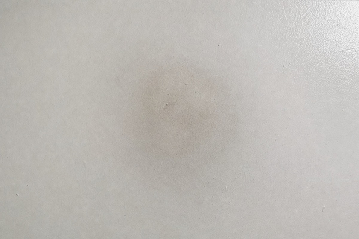 Subtiele grijze roetschaduw op een wit plafond boven de plek waar een paraffinekaars stond